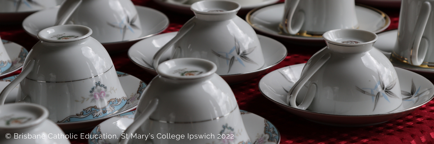 White teacups and saucers arranged upside down on a table with a red tablecloth
